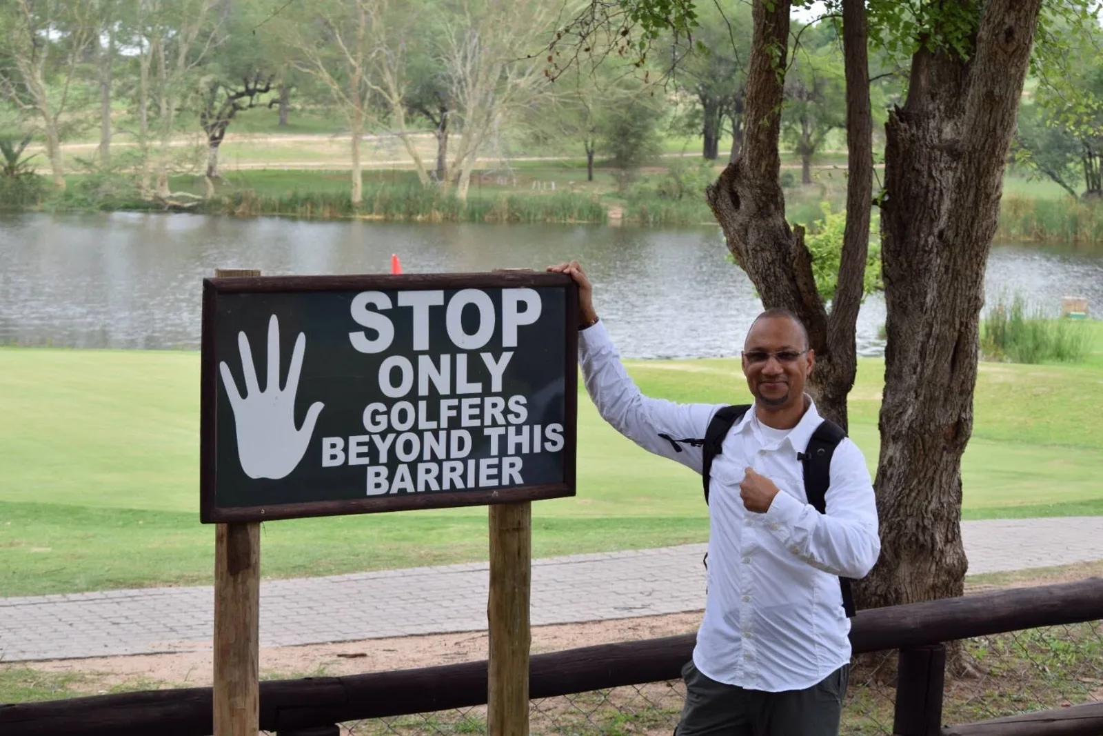 Loren beside a 'Stop - only golfers beyond this barrier' sign
